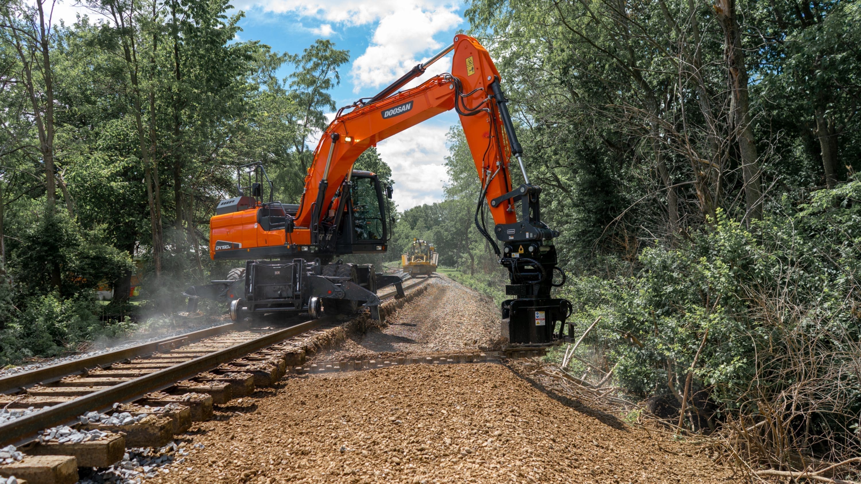 BALLAST BLASTER UNDERCUTTER - PIN GRAB DymaxRail Ballast Blaster undercutter operating on Doosan wheel excavator with hi-rail gear, removing fouled ballast with second hi-rail machine working down the track