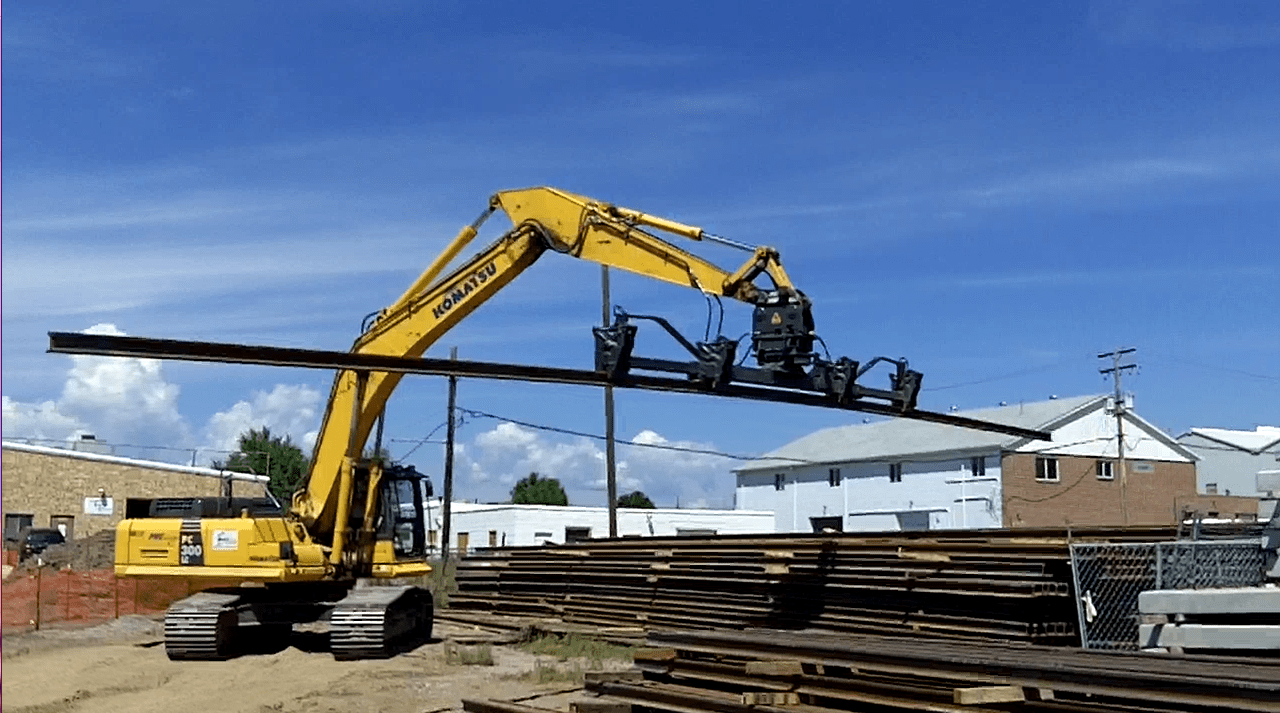 DymaxRail Rail Handler LG mounted on Komatsu excavator lifting long rail from storage pile