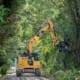 Cat excavator using Dymax 21-inch tree shear to trim branches overhanging railroad right-of-way