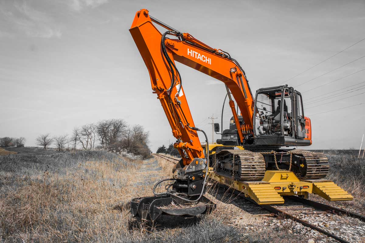 Dymax VortexMax brush cutter mounted on excavator clearing overgrown brush along railroad track corridor