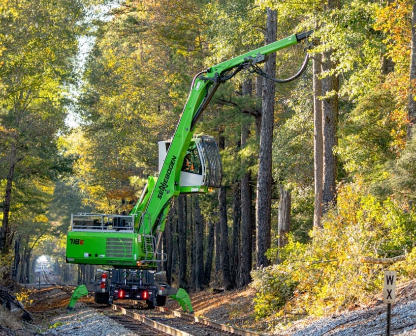 DymaxRail Rail Rider WX Hi-Rail System – Sennebogen Wheel Excavator DymaxRail Rail Rider WX hi-rail system on Sennebogen wheel excavator clearing trees on railway right-of-way