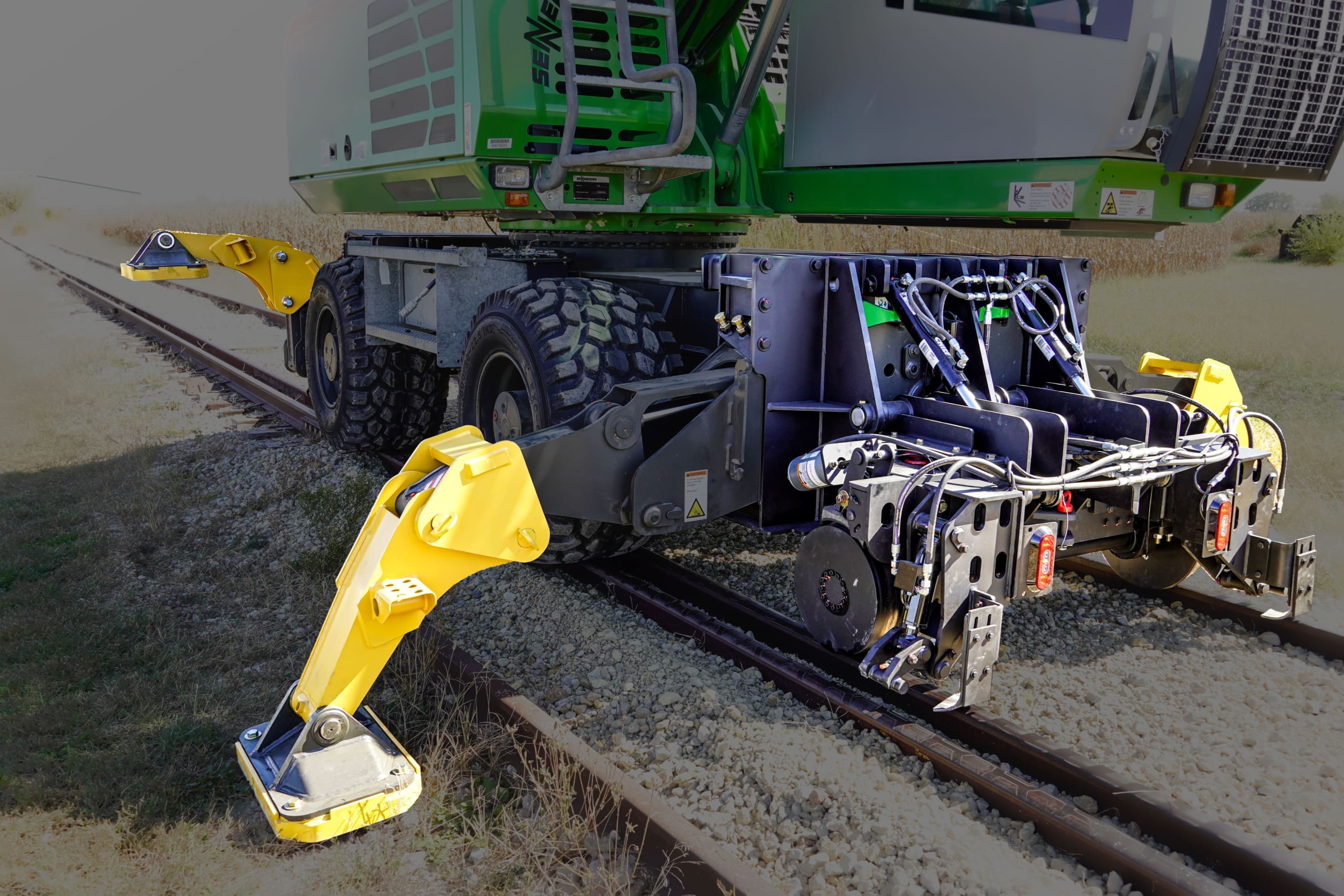 Dymax Rail Rider WX4S hi-rail system mounted on a Sennebogen 718 4-stabilizer wheel excavator, showing the railgear deployed on track.