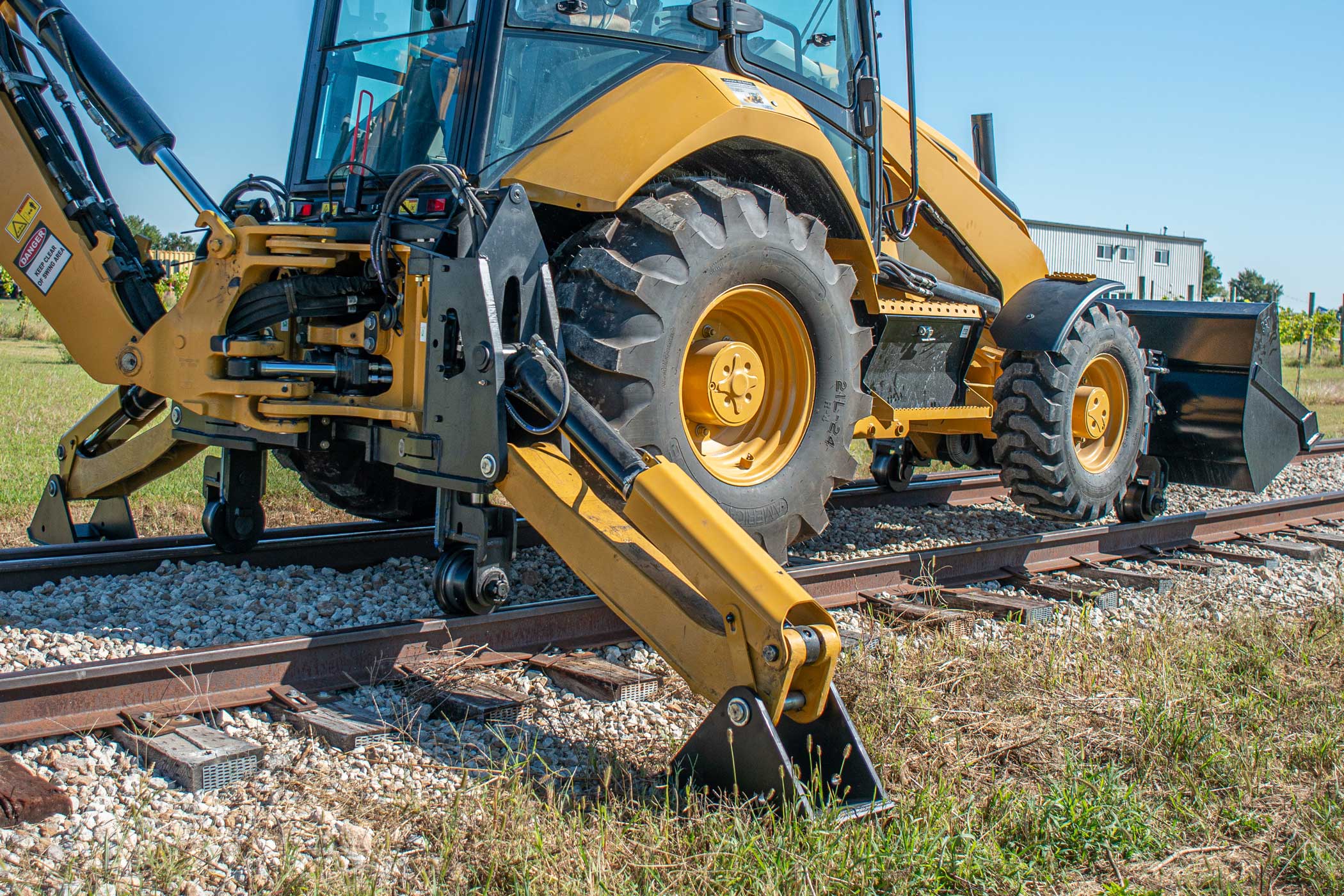 Caterpillar 420 backhoe loader equipped with Dymax Rail Rider BL Stabilizer-Mounted hi-rail system