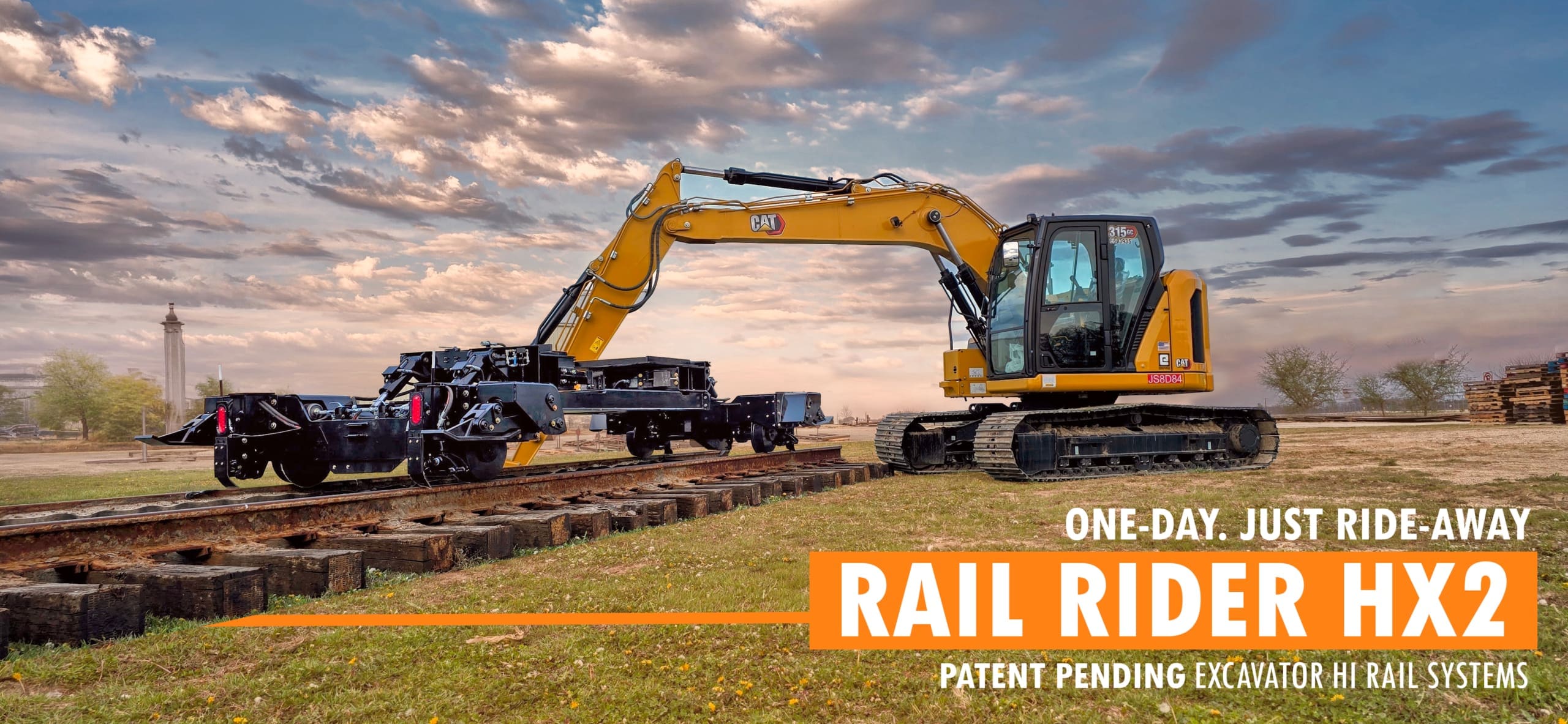 dymax-rail-rider-x2-hi-rail-track-excavator-on-rail-sunset Track excavator with Dymax Rail Rider X2 detachable hi-rail system on railroad track at sunset