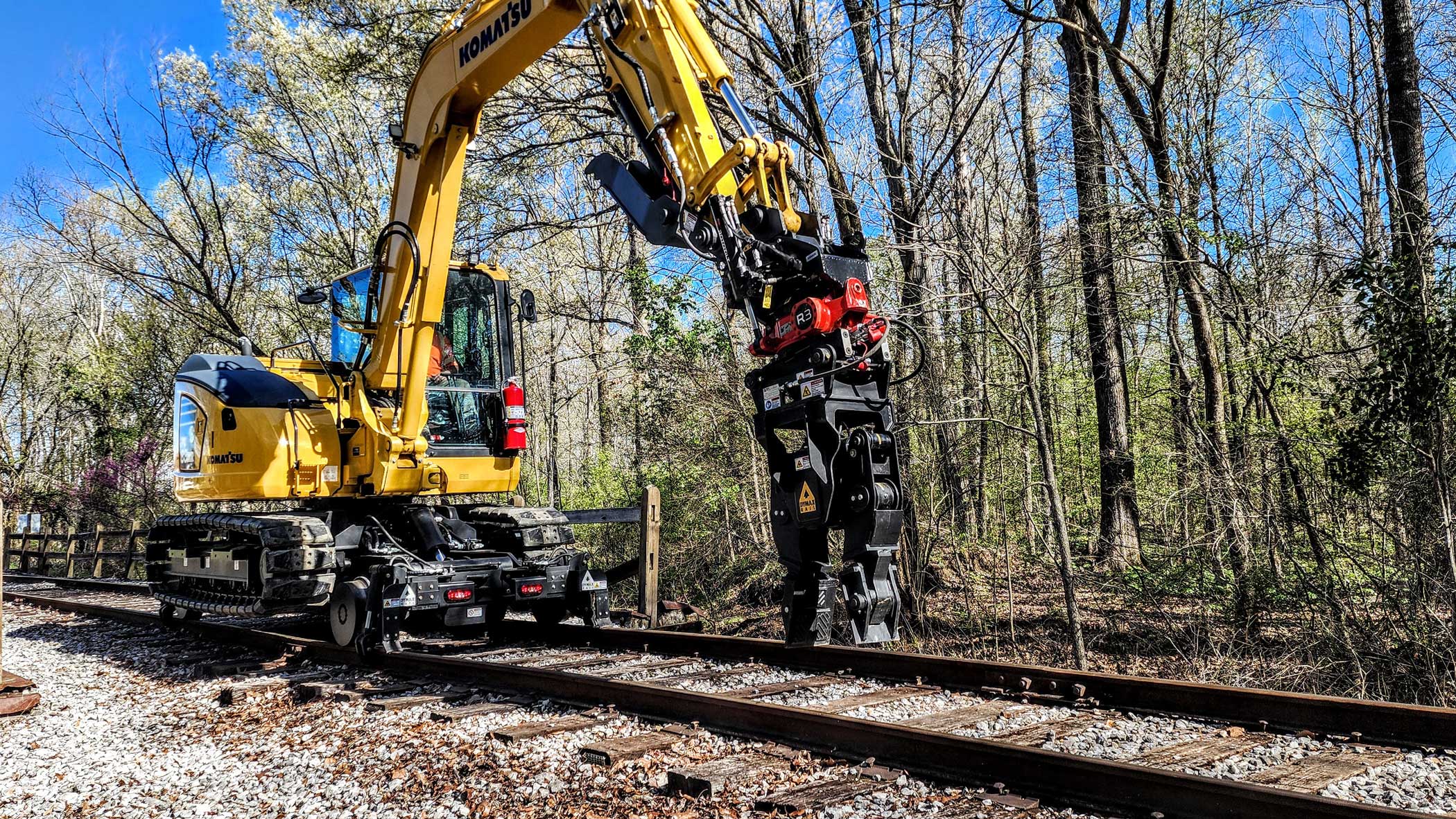 DymaxRail Tie Inserter on Komatsu PC88 with Hi-Rail System DymaxRail Tie Inserter mounted on Komatsu PC88 excavator with hi-rail attachment system inserting railroad tie on track