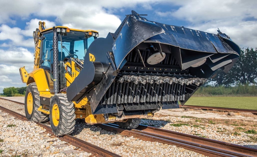 DymaxRail Ballast Broom attachment mounted on Cat backhoe loader on railroad track