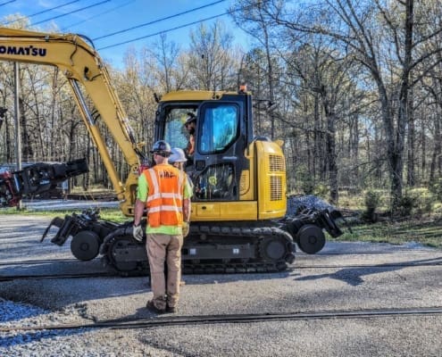 Hi-rail excavator attachment mounted on an excavator during an on-track rail maintenance orientation in Alabama.