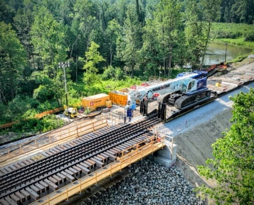 Crawler crane delivered to the bridge replacement site using rail-based equipment transport.
